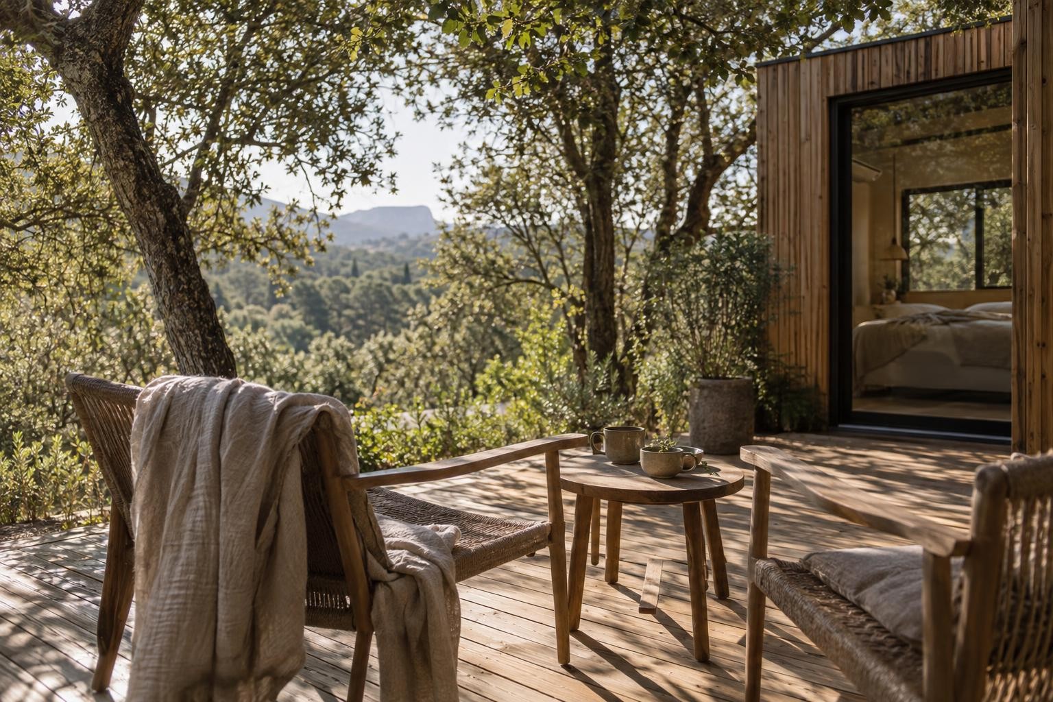 Terrasse en bois d’une Tiny House sous les chênes, avec une table et deux tasses au matin