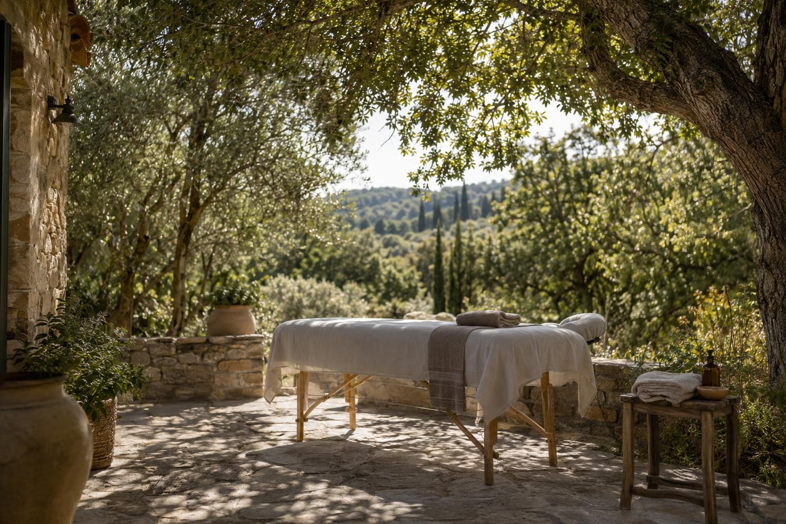 Table de massage sous un grand chêne, préparée avec du linge clair sur une terrasse provençale