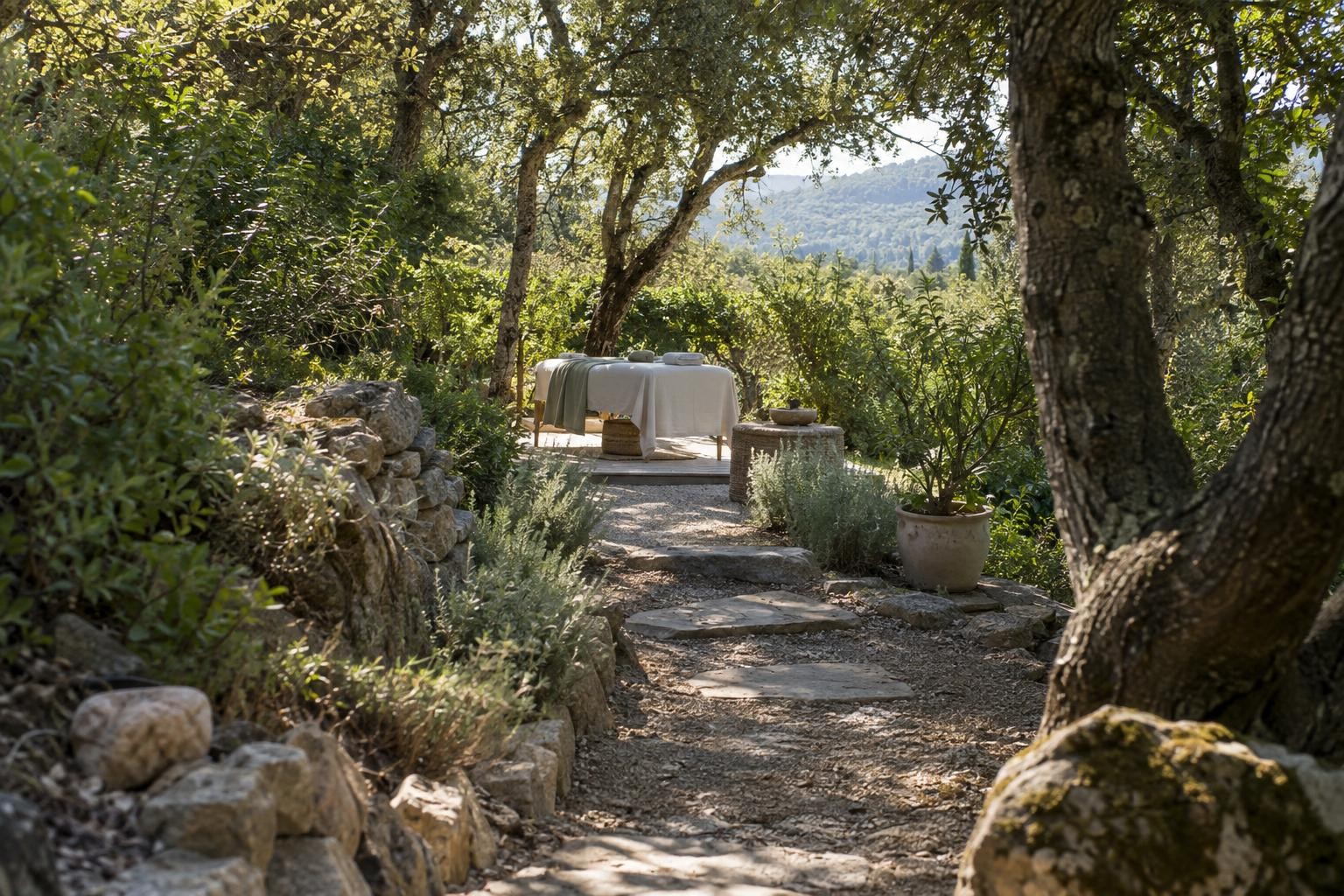 Chemin ombragé sous les chênes menant à un espace de soin en plein air en Provence